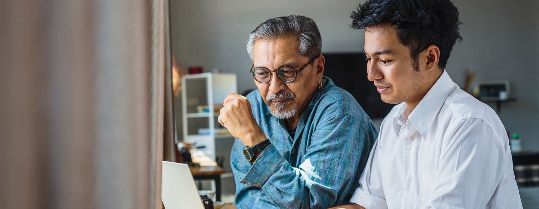 older man and young man looking at a laptop